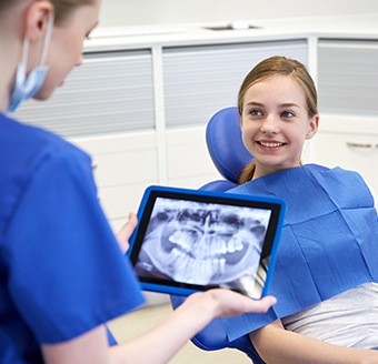 Little girl smiling at dentist holding x-rays