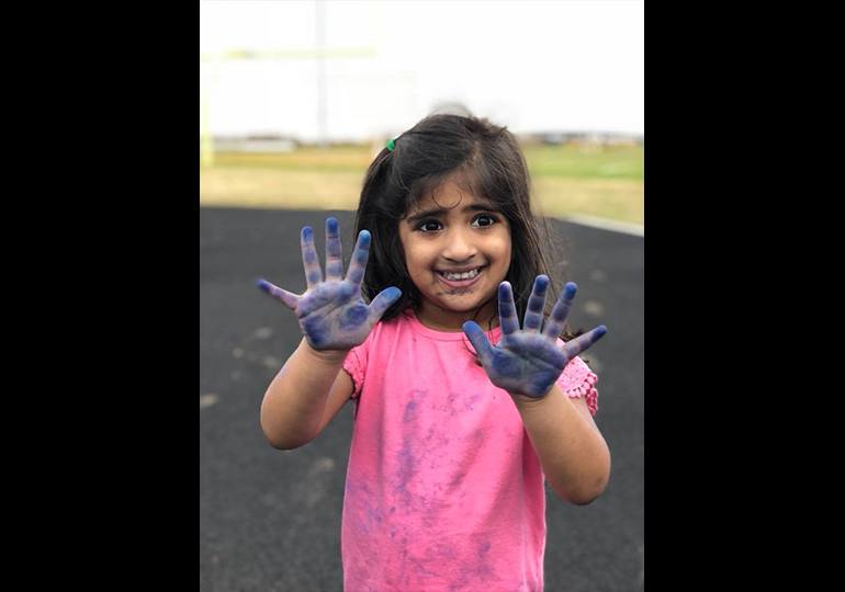 Little girl with blue paint on her hands
