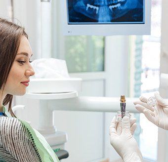 Dentist showing dental patient an implant model