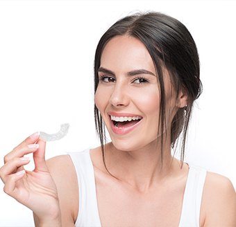 Smiling woman holding Invisalign tray